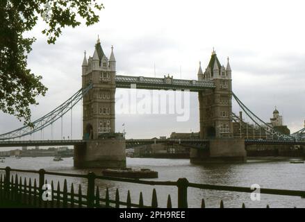 Nach London. 1984. Blick auf die Tower Bridge von Tower Wharf am Nordufer der Themse in London, England. In der Ferne ist der weiße Turm von Anchor Brewhouse zu sehen, der sich an der Shad Thames 50 befindet. Am ufer der Brücke in surrey wird ein Gerüst errichtet. Stockfoto