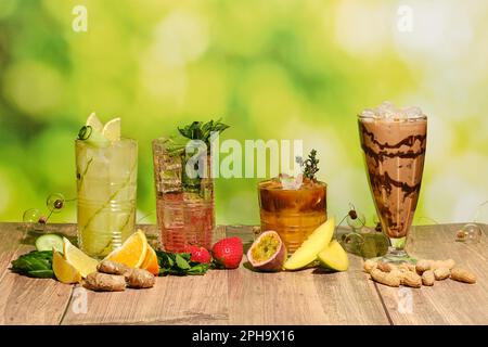Set aus bunten, erfrischenden Erfrischungsgetränken im Sommer auf einem Holztisch mit Zutaten Stockfoto