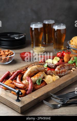 Verschiedene leckere Snacks und Bier auf einem Holztisch Stockfoto