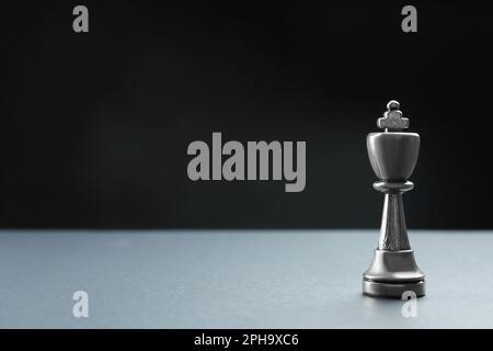 Metallkönig auf dem Tisch vor dunklem Hintergrund, Platz für Text. Schachfigur Stockfoto
