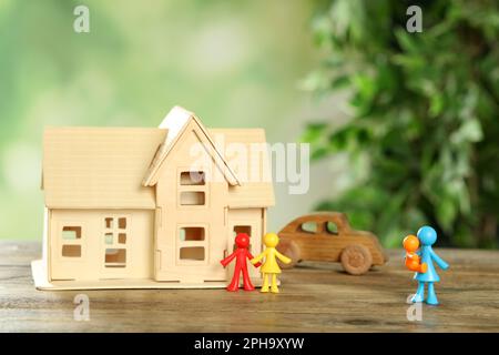MYKOLAIV, UKRAINE - 04. JANUAR 2022: Bunte menschliche Figuren, Hausmodell und Spielzeugauto auf Holztisch. Leihmutterschaftskonzept Stockfoto