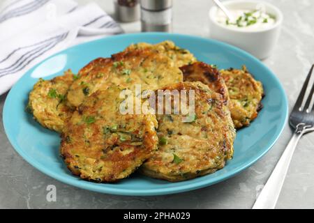 Leckere Zucchini-Pfannkuchen, serviert auf grauem Tisch, Nahaufnahme Stockfoto