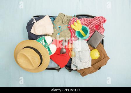 Offener Koffer und Gepäck mit verschiedenen eingepackten Kleidungsstücken. Reisekonzept. Draufsicht Stockfoto