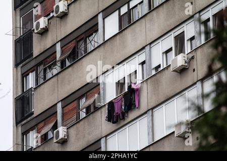 Bild von Kleidung, die an Fenstern trocknet und hängt, eines kommunistischen Gebäudes in den Straßen von Belgrad, Serbien. Stockfoto