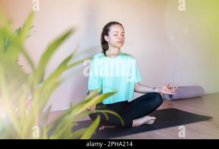 Brünette Frau, die in Lotusstellung meditiert. Stockfoto