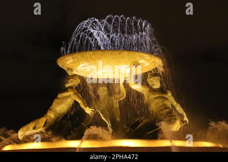 Der Tritons-Brunnen (bei Nacht) ist ein Brunnen, der sich direkt vor dem Stadttor von Valletta, Malta, befindet. Es besteht aus drei Bronze-Tritonen, die ein großes Becken bilden, auf einem konzentrischen Boden aus Beton ausbalanciert und mit Travertinplatten verkleidet sind. Der Brunnen ist eines von Maltas wichtigsten modernistischen Wahrzeichen. Entwickelt und gebaut zwischen 1952 und 1959. Der Busbahnhof und der Bahnhof befinden sich in der Nähe. Stockfoto