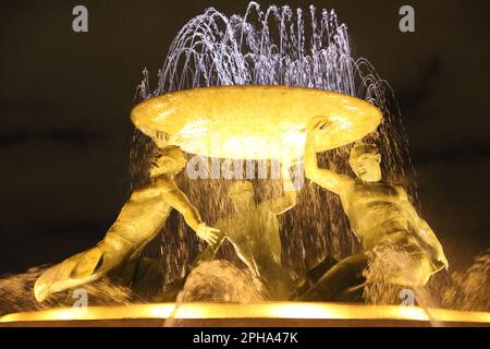 Der Tritons-Brunnen (bei Nacht) ist ein Brunnen, der sich direkt vor dem Stadttor von Valletta, Malta, befindet. Es besteht aus drei Bronze-Tritonen, die ein großes Becken bilden, auf einem konzentrischen Boden aus Beton ausbalanciert und mit Travertinplatten verkleidet sind. Der Brunnen ist eines von Maltas wichtigsten modernistischen Wahrzeichen. Entwickelt und gebaut zwischen 1952 und 1959. Der Busbahnhof und der Bahnhof befinden sich in der Nähe. Stockfoto