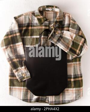 Neue schwarze Eco Einkaufstasche mit Platz für Text. Bag-Modell-Vorlage, Draufsicht. Kleiderschrank mit Hemd. Kleidung und Accessoires. Weißer Hintergrund, Kopierbereich. Unisex-Karohemd Stockfoto