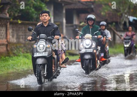 Sidemen, Bali, Indonesien - 24. März 2023: Unidentifizierte Personen pendeln durch eine überflutete Straße. Stockfoto