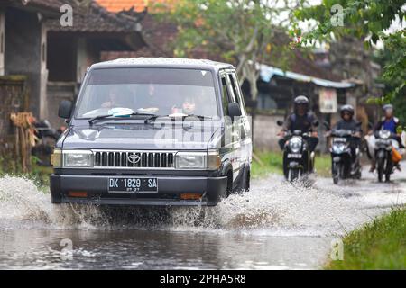 Sidemen, Bali, Indonesien - 24. März 2023: Unidentifizierte Personen pendeln durch eine überflutete Straße. Stockfoto