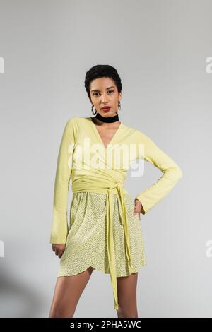 Kurzhaarige afroamerikanische Frau im Frühlingsoutfit, auf grauem Hintergrund, Stockbild Stockfoto