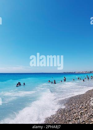 Eine idyllische Strandszene mit einer Gruppe glücklicher Menschen, die in der Sonne spielen und lachen, Nice Ville, Frankreich Stockfoto