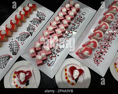 Showcase mit Süßigkeiten. Farbig сakes auf weißen Platten auf schwarzem Tisch. Stockfoto