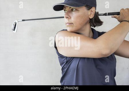 Golfer mit Cap hält ihren Iron Golf Club an einem sonnigen Tag in der Schweiz. Stockfoto