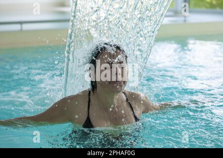 Frauengesicht Entspannen in einem Hydromassage-Pool mit fallendem Wasser in der Schweiz. Stockfoto