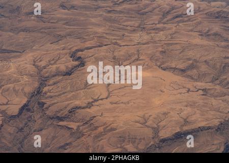 Dramatische Luftaufnahme der Textur und Muster der kargen Wüstenlandschaft aus einem Flugzeug im Nahen Osten. Stockfoto