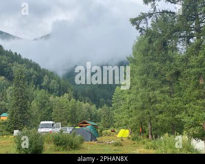 Altai, Russland - 02. Oktober 2022 Ruhestätten mit einem Pavillon und Zelten mit Autos von Touristen in der Nähe des Flusses in Altai in der Nähe der Berge mit Nebel. Stockfoto