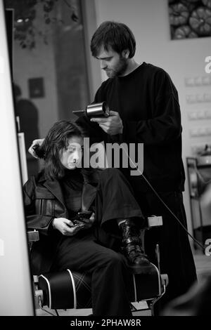 Mann Friseur trocknet weibliches Haar mit Haartrockner nach dem Waschen Stockfoto