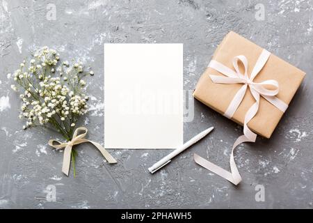 Hochzeitsmodell mit weißer Papierliste und Blumen Zigeuner auf farbigen Tisch Blick flach liegend. Leere Grußkarten und Briefumschläge. Wunderschönes Blumendesign Stockfoto