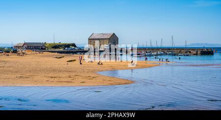 Panoramablick über Elie Beach, mit Urlaubern, die die Sommersonne genießen, zum Elie Hafen im East Neuk of Fife, Schottland, Großbritannien Stockfoto