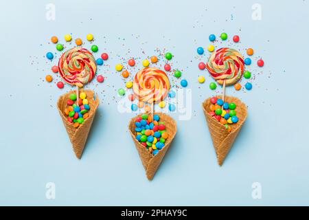 Waffelkonus voller traditioneller Süßigkeiten, die auf farbigen Hintergrund fallen, mit Platz für Kopien. Frohes Weihnachtsangebot. Stockfoto