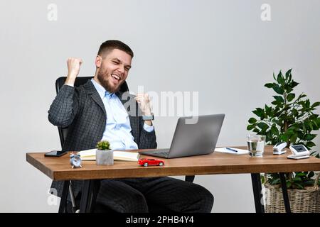 Mann sitzt auf einem Stuhl am Tisch und ruht sich aus, benutzt Laptop Stockfoto