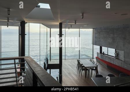 Blick auf Küche und Essbereich von der Treppe. Ravine House, South Coogee, Australien. Architekt: Rolf Ockert Architect, 2023. Stockfoto