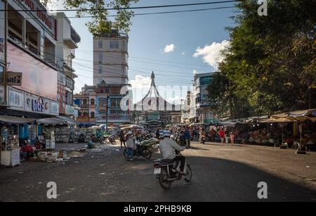 Ein Mann fährt mit dem Motorrad in Richtung der überfüllten Straßen vor dem Wahrzeichen Central Market in Pleiku im zentralen Hochland Vietnams. Stockfoto