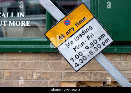 Ein Schild an der Straße, wo man nicht warten und nicht laden kann, ist schräg umgebogen, da die Befestigungsstange verbogen war. Das Schild befindet sich in der Nähe und auf Straßenebene Stockfoto