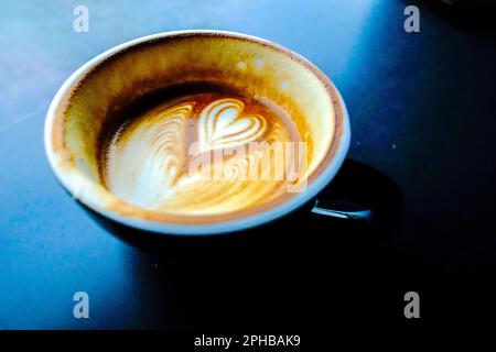 eine tasse heißen Latte-Kaffee mit herzförmiger Schaummilch auf dunklem Hintergrund Stockfoto