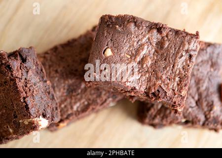 Eine Charge frisch gebackener dreifach-Schokoladen-Brownies auf einer Holzplatte. Die Brownies sind noch warm und klebrig. Ein Genuss Stockfoto