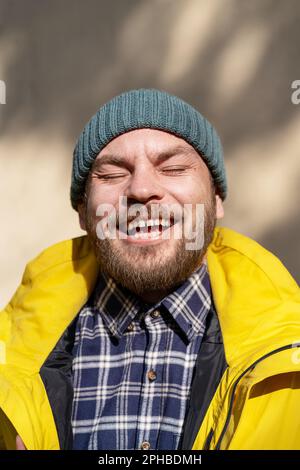 Porträt: Eigenartiger erwachsener Mann, der die Frühlingssonne genießt und mit geschlossenen Augen lächelt. Stockfoto