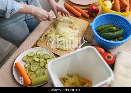 Frau kocht Mittagessen und kompostiert organische Lebensmittelabfälle in einem bokashi-Behälter. Weibliche Person bereitet Frühstück zu und recycelt Reste in einem Kompost Stockfoto