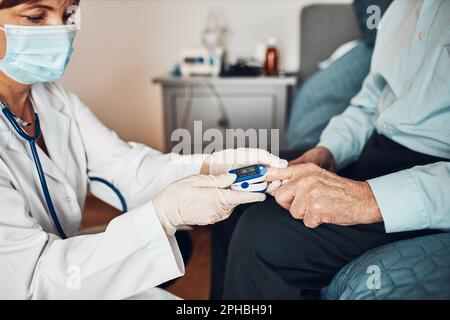 Arzt zur Messung des Sauerstoffsättigungsgrads des Blutes und der Herzfrequenz älterer Patienten mit dem Pulsoxymeter. Heimbehandlung des Virus. Ich Überprüfe Es Stockfoto