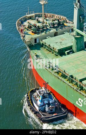 Schleppboot in Aktion, das das Frachtschiff lenkt Stockfoto