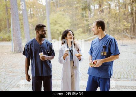 Lächelnde, multiethnische Mitarbeiter im Gesundheitswesen, die in der Pause sprechen Stockfoto