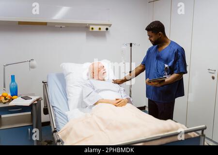 Krankenschwester mit Hand auf Schulter des im Krankenhaus liegenden Seniorpatienten Stockfoto
