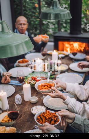 Seniorin hält Karottenschüssel während der Dinnerparty Stockfoto
