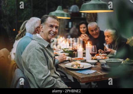 Portrait eines glücklichen Seniorenmannes mit Freunden während der Dinnerparty Stockfoto