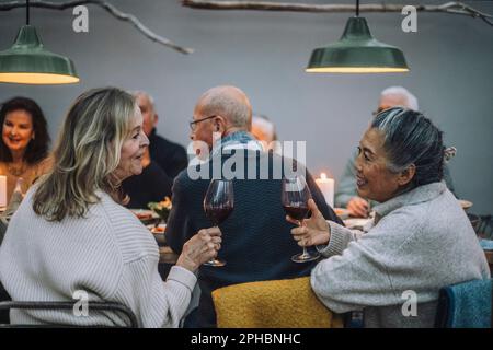 Seniorinnen mit Weingläsern, die sich auf der Dinnerparty unterhalten Stockfoto