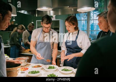 Koch-Mitarbeiterin des männlichen Schülers während des Kochkurses in der Küche Stockfoto