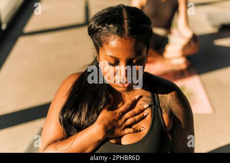 Eine Frau in Übergröße mit der Hand auf der Brust, die Atemübungen im Rückzugszentrum übt Stockfoto