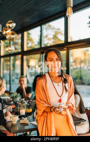 Porträt einer Frau, die verschiedene Edelsteine hält, während sie im Rückzugszentrum steht Stockfoto