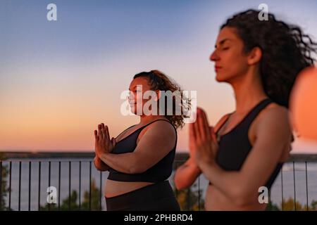 Lächelnde Frau mit Händen, die von einer Freundin bei Sonnenuntergang gefesselt wurden Stockfoto