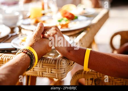 Zugeschnittenes Bild eines heterosexuellen Paares, das am Tisch im Resort Händchen hält Stockfoto