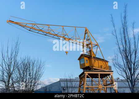 Ein gelber Industriekran vor einem blauen Himmel in der Nähe der Hafendocks von Granville Island, Vancouver, British Columbia Stockfoto