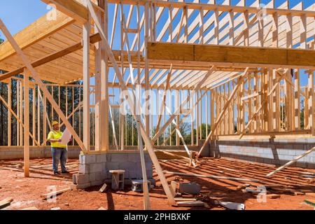 Bauunternehmer, der den Architekturplan während der Bauarbeiten auf der Baustelle verwendet Stockfoto