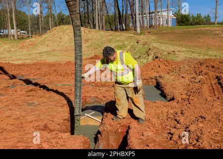 Betonverleger beim Gießen mit ausrichtender automatischer Pumpe für Fundamentbau Stockfoto