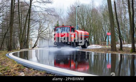 Minsk, Weißrussland - 08. April 2022: Reinigung der Kehrmaschine wäscht die Asphaltstraße mit Wasserspray. Stockfoto