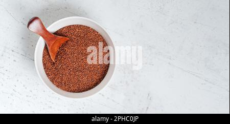 Kresse ( Lepidium sativum ) Samen in einer kleinen weißen Schüssel mit Holzlöffel, Blick von oben, Platz für Text - leerer Steintisch - rechte Seite Stockfoto